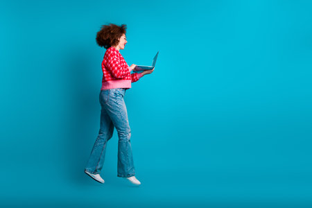 Full length photo of adorable lovely girl wear red cardigan jumping reading modern device empty...