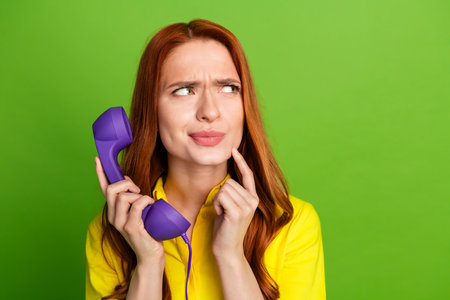 Photo of lovely cute woman wear yellow trendy clothes hold handset look empty space decision isolated on green color backgroundの写真素材