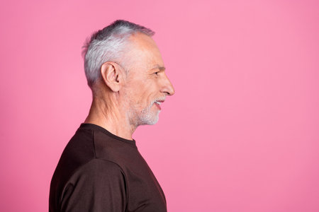 Side profile of nice man with white gray beard dressed brown t-shirt look at discount empty space isolated on pink color backgroundの写真素材