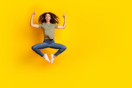 Full size photo of cheerful girl dressed striped t-shirt levitating directing at sale empty space...