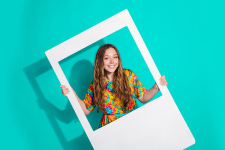 Photo portrait of attractive teen woman hold instant photo frame dressed stylish colorful clothes isolated on cyan color backgroundの写真素材
