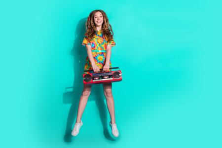Full size photo of pretty teen girl jumping hold boombox wear trendy colorful outfit isolated on...