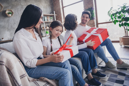 Photo of cheerful excited boyfriend girlfriend kids wear casual looks getting new year presents indoors room home houseの写真素材