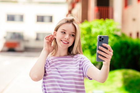 Photo of adorable sweet lady wear striped t-shirt enjoying walking recording video modern device outdoors urban city streetの写真素材