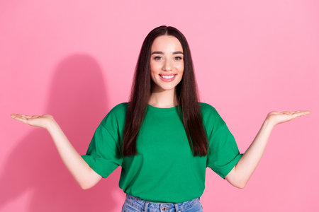 Photo of shiny attractive lady dressed green t-shirt comparing arms empty space isolated pink color backgroundの写真素材