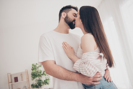 Photo of attractive trendy cheerful married young couple spending free kissing time move new apartment home interior indoorsの写真素材