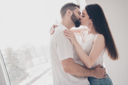 Photo of attractive trendy cheerful married young couple spending free time kissing embrace move new...