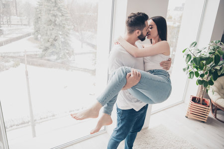 Photo of attractive trendy cheerful married young couple kissing husband hold wife move new apartment home interior indoorsの写真素材