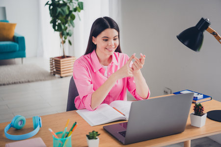 Photo of shiny attractive girl dressed pink shirt doing hometasks counting fingers modern device...