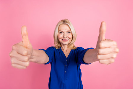 Photo portrait of pretty senior female thumb up approve wear trendy blue outfit isolated on pink...