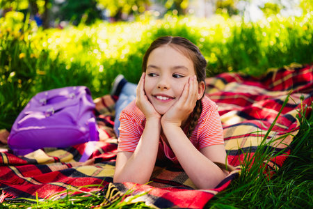 Full length photo of adorable little girl have fun outside activity lying ground picnic enjoy summer weekend pastime fresh air outdoorの写真素材