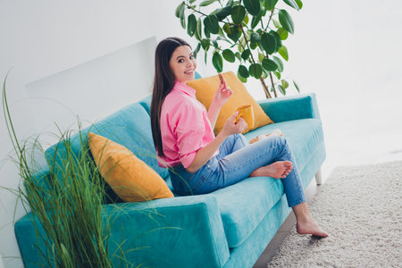 Photo of cute attractive girl dressed pink shirt drinking coffee eating snacks indoors house apartment roomの写真素材