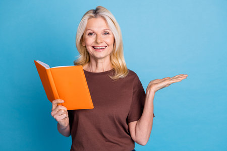 Photo of adorable clever smart woman wear trendy brown clothes hold book empty space isolated on blue color backgroundの写真素材