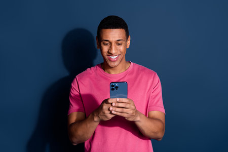 Photo of young funny man using mobile phone chatting with girlfriend happy received sms isolated on...