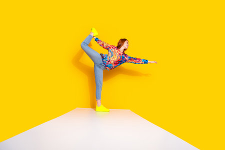 Full body photo of attractive young woman flexible dancing dressed stylish colorful clothes isolated on orange color backgroundの写真素材
