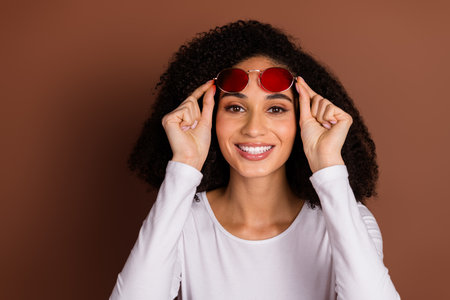 Photo of pretty young girl touch sunglass wear pullover isolated on brown color background