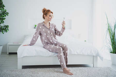 Photo of pretty lovely woman wear stylish pajama morning sit comfy bedroom daylight indoorsの写真素材