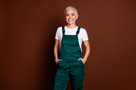 Photo of cheerful charming lovely nice woman wear green overall isolated on brown color backgroundの写真素材