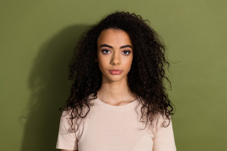 Photo of serious confident gorgeous girl with wavy hairstyle dressed beige t-shirt staring at you isolated on khaki color backgroundの写真素材