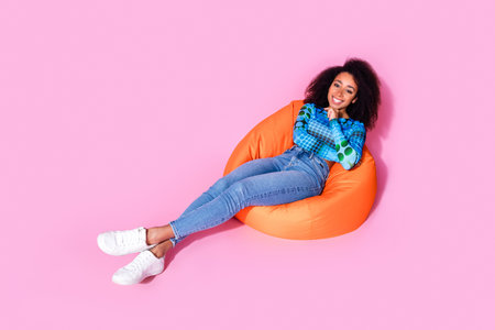 Full body photo of attractive young woman sit orange beanbag dressed stylish blue clothes isolated...