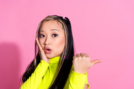 Photo of astonished girl with dyed hairdo dressed yellow turtleneck directing at logo empty space...