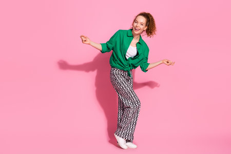 Full length photo of shiny attractive lady dressed green shirt having fun empty space isolated pink color backgroundの写真素材
