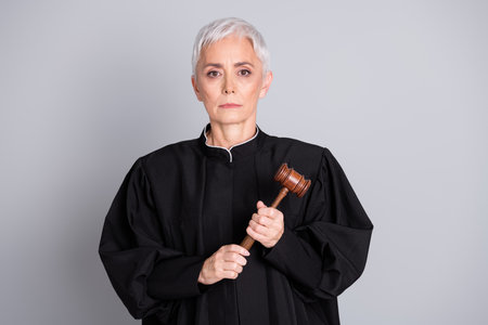 Photo of serious woman judge hold touch gavel for verdict isolated grey color backgroundの写真素材
