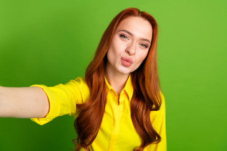 Photo portrait of pretty young girl take selfie photo kissing wear trendy yellow outfit isolated on green color backgroundの写真素材