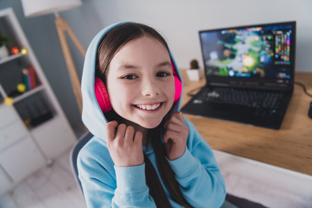 Photo of cheerful glad funny adorable girl little gamer playing online video game relax rest indoors houseの写真素材