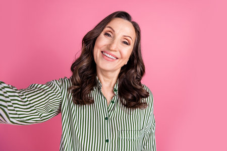 Photo of nice aged lady make selfie wear striped shirt isolated on pink color background