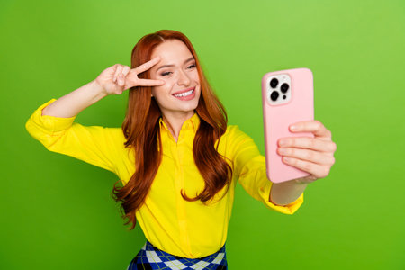 Photo of cheerful positive cute woman wear yellow trendy clothes make video vlog isolated on green color backgroundの写真素材