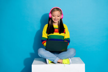 Full body photo of attractive young woman sit cube headphones netbook dressed stylish striped...