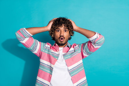 Photo of shocked impressed man wear trendy striped clothes isolated on cyan color background
