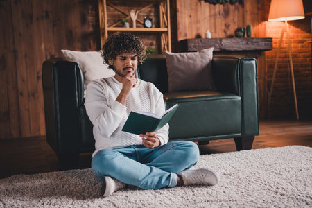 Photo of attractive doubtful guy wear white sweatshirt reading book indoors room home house