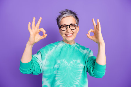 Photo portrait of lovely pensioner lady show okey approve dressed stylish green garment isolated on...