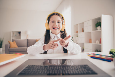 Photo portrait of cute adorable girl headphones netbook count fingers math speak web camera remote lesson education from home indoorsの写真素材