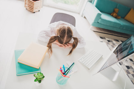 Photo portrait of small cute daughter lying table sleeping cry remote education home schooling isolated indoors backgroundの写真素材