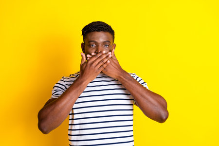 Portrait of nice young man cover mouth wear striped t-shirt isolated on vibrant yellow color backgroundの写真素材