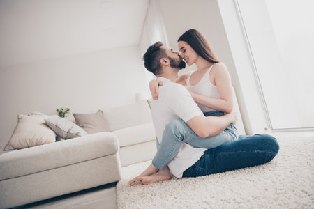 Photo of adorable sweet couple wear casual shirts kissing cuddling enjoying weekend together indoors...