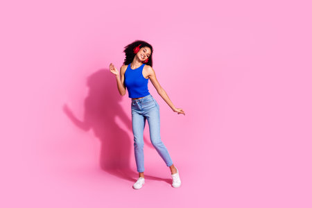 Full size photo of pretty young girl earphones dance listen music wear trendy blue outfit isolated on pink color backgroundの写真素材