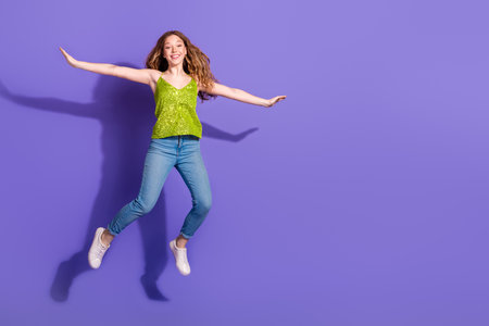 Full size photo of pretty teenager girl jump flying spread hands wings wear trendy green outfit...