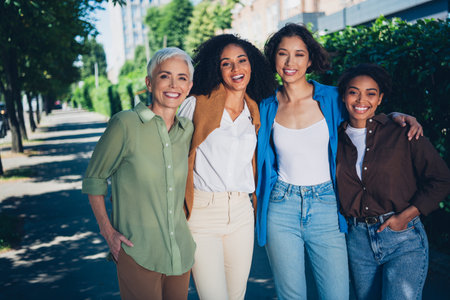 Photo portrait of happy multi generational women hugging unity team having fun together multiracial friends outdoor city parkの写真素材