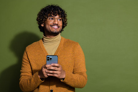 Photo portrait of pretty young male hold gadget look empty space wear trendy brown outfit isolated...