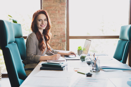 Photo of happy charming lady assistant wear formal shirt texting modern gadget write book indoors workshop workstation loftの写真素材