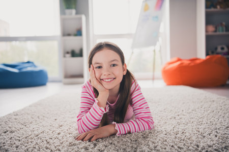 Full body photo of cute small schoolgirl lying floor soft carpet dreamy relaxed home education...