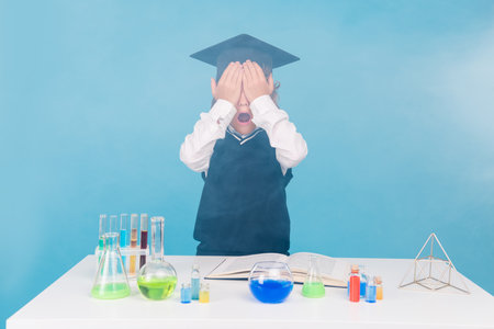 Photo of funny cute small boy learn chemistry subject failed experiment research isolated on blue color backgroundの写真素材