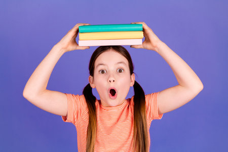 Photo portrait of cute little girl hold books head amazed dressed stylish red clothes isolated on...