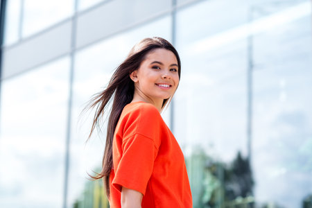 Photo of pretty teen good mood girl turn around look camera cheerful wear red clothes walk outside urban city parkの写真素材