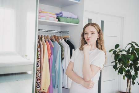 Photo of sweet pretty teen girl minded choose garment wear pajama white interior bedroom apartmentの写真素材