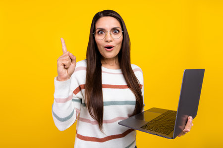 Photo of mature brunette hair business woman pointing finger up find genius idea when was using laptop isolated on yellow color backgroundの写真素材
